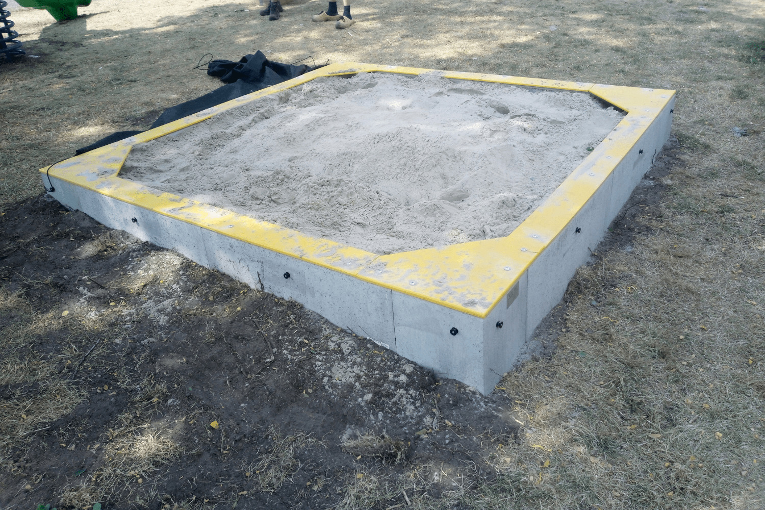 Zandbak betonranden met PE-afdeklijst bij speelplek vluchtelingen Vredense Hof in Winterswijk